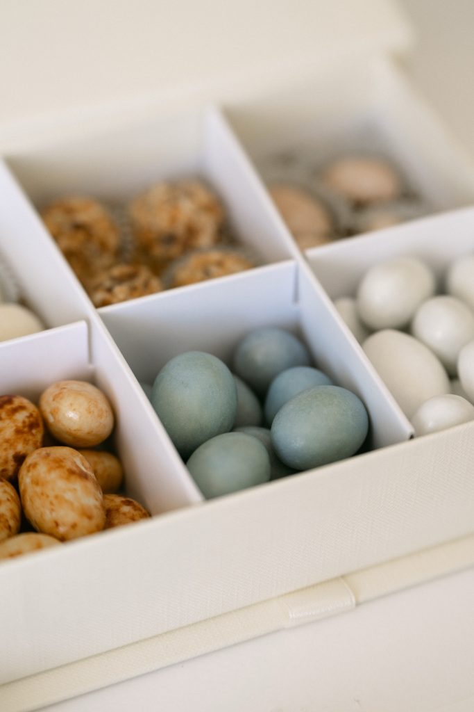Dettaglio di un cofanetto a scomparti con confetti azzurri e bianchi e praline