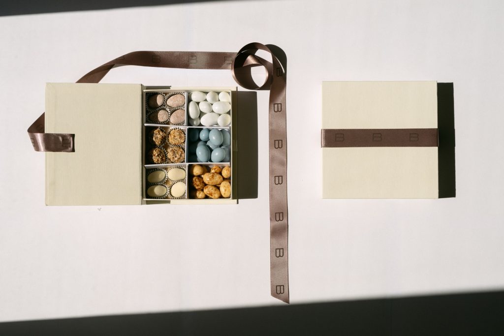 Cofanetto aperto con confetti e praline e scatola chiusa con fascia marrone