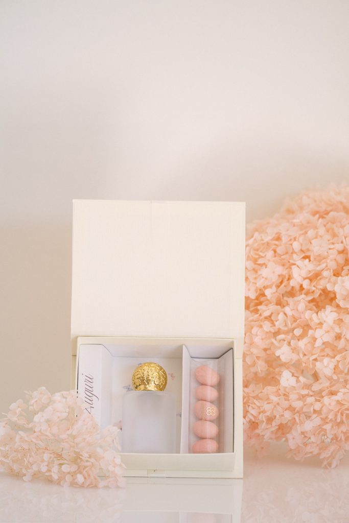Scatolina avorio con il coperchio alzato, confetti rosa e pralina dorata