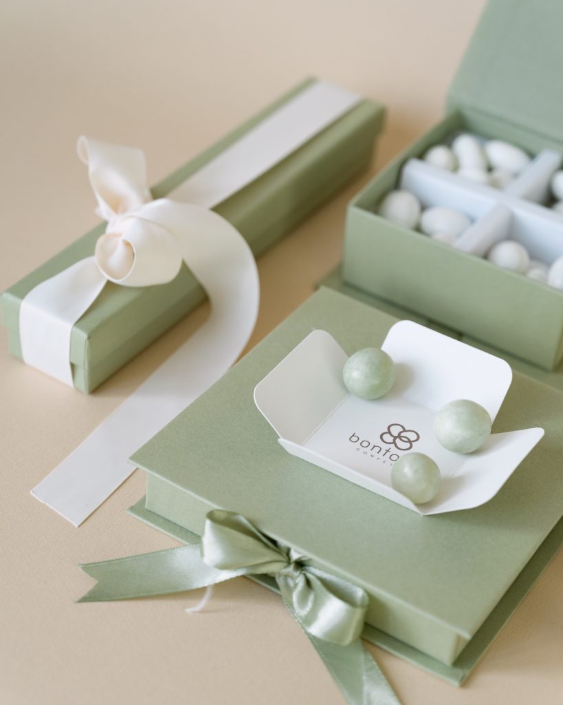 Scatole verde salvia con confetti bianchi e verdi e astuccio con nastro avorio