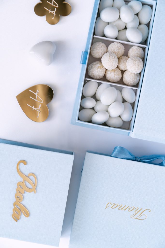 Cofanetto azzurro a scomparti con confetti e praline bianche e scatole con nomi in oro