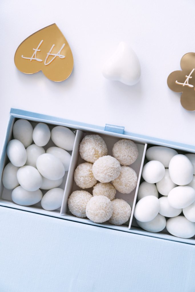 Cofanetto azzurro a scomparti con confetti e praline bianche e cuori dorati con le iniziali
