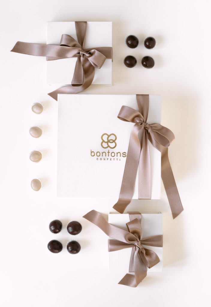 Scatole bianche con il marchio Bontons e fiocchi tortora, praline al cioccolato e confetti