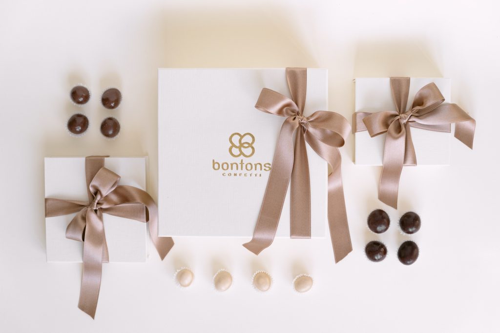 Scatole bianche con il marchio Bontons in oro e nastri tortora, con praline al cioccolato
