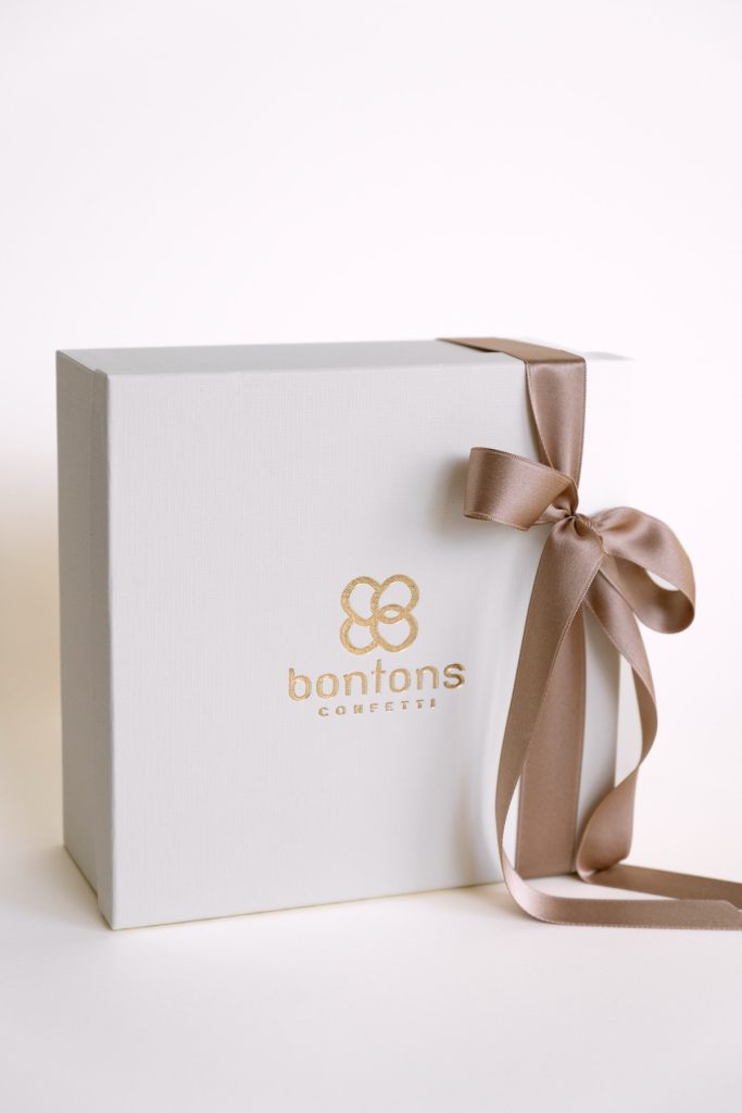 Scatola bianca con il marchio Bontons in oro e nastro tortora