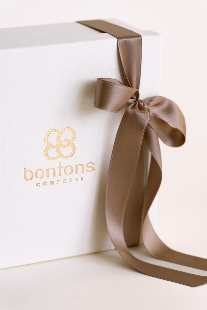 Scatola bianca con il marchio Bontons in oro e fiocco tortora, dettaglio