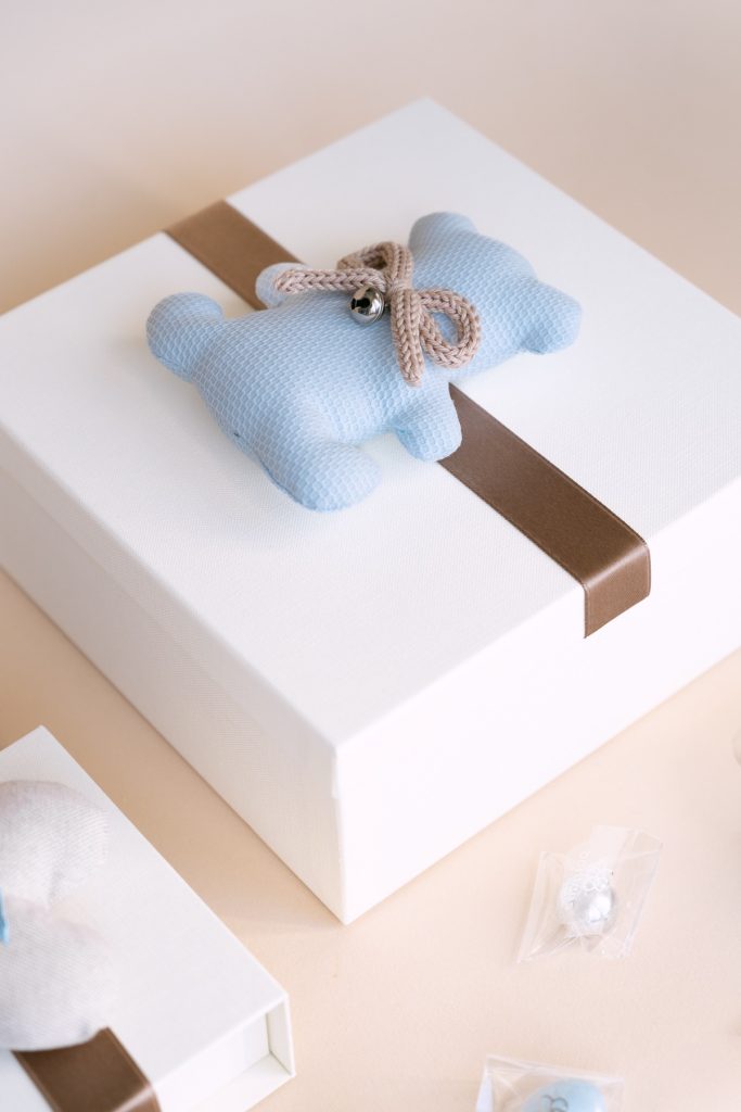 Scatola bianca con orsetto azzurro in tessuto e fascia marrone, dettaglio