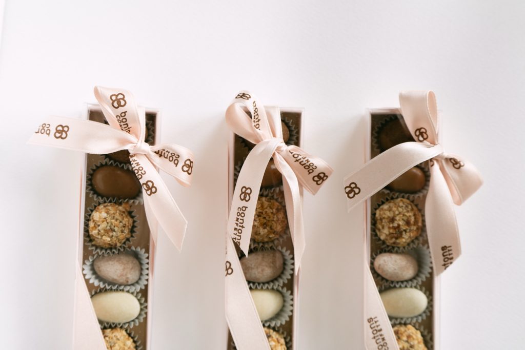 Astucci trasparenti con confetti e praline e nastri rosa cipria