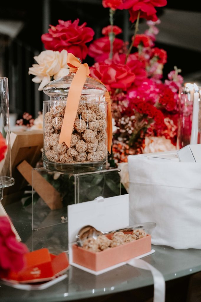 Vaso di vetro con Nougatine e nastro arancio tra rose fucsia e bianche