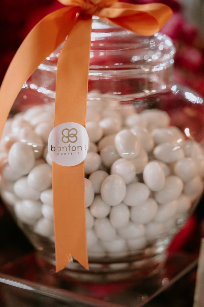Vaso di vetro con confetti bianchi, nastro arancio e bollino Bontons Confetti